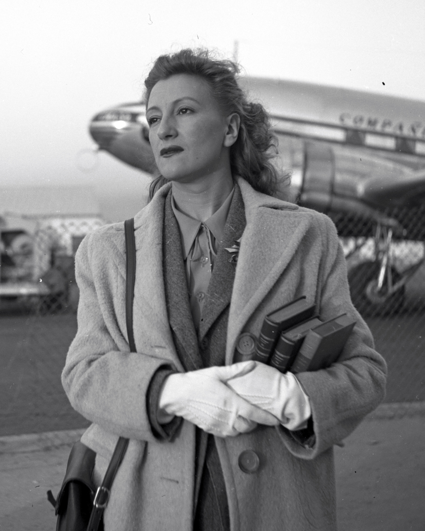 Esperanza Lopez Mateos at the airport runway with books dressed for travel