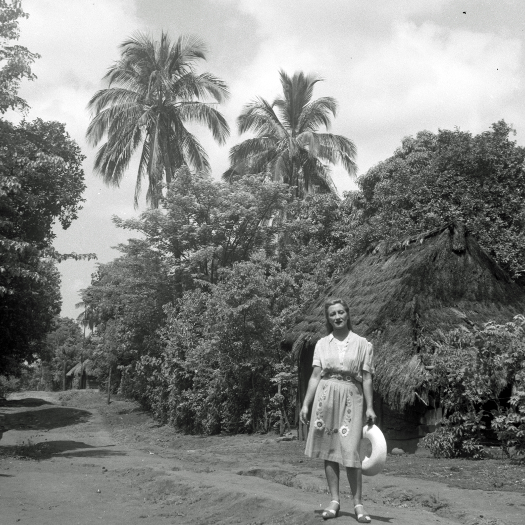 Esperanza standing on dirt road in front of thatched house