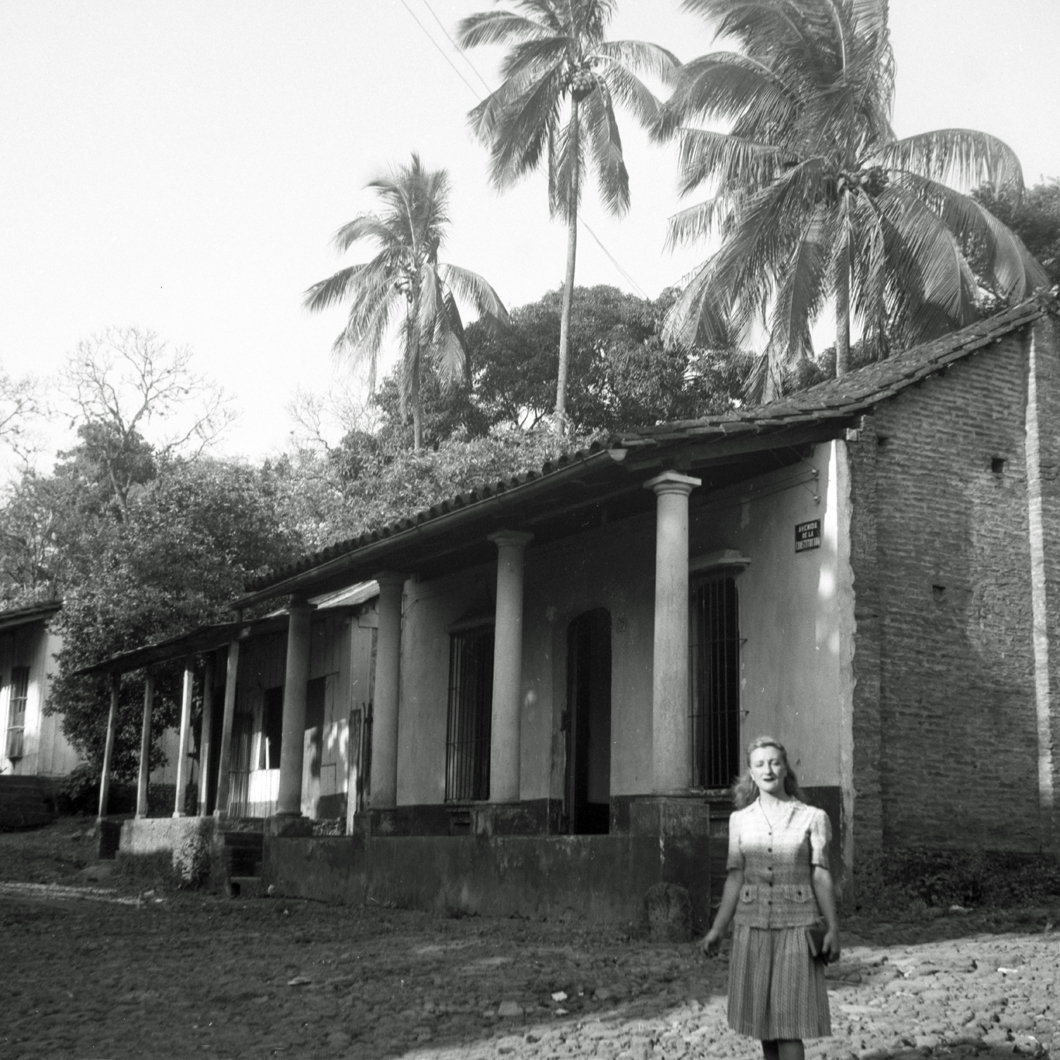 Esperanza standing before house in town