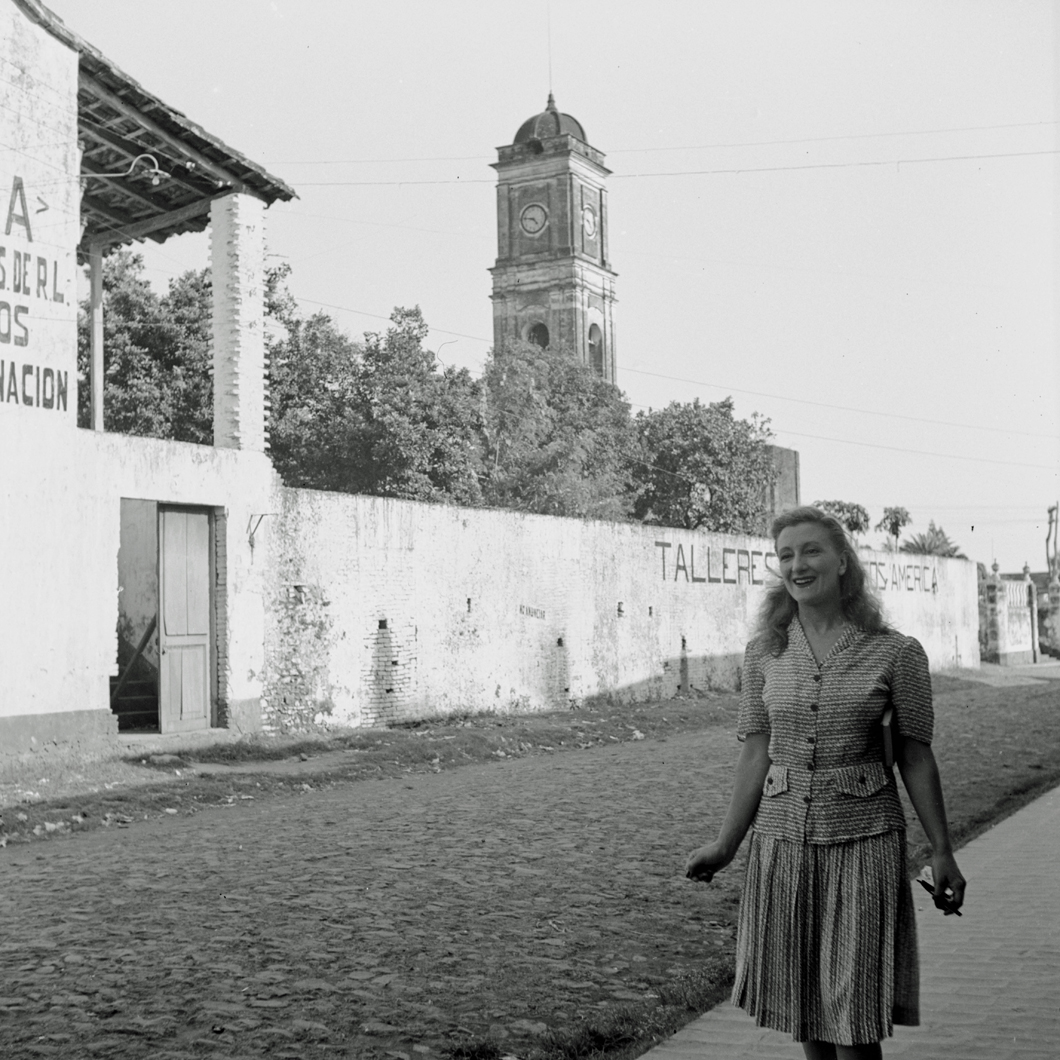 Esperanza standing before house in town